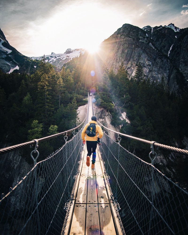 A guy running forward on a wood bridge